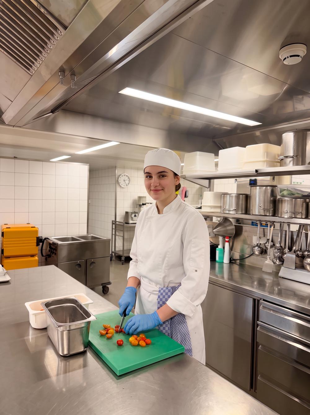 Junge Küchenangestellte schneidet Tomaten in der Küche